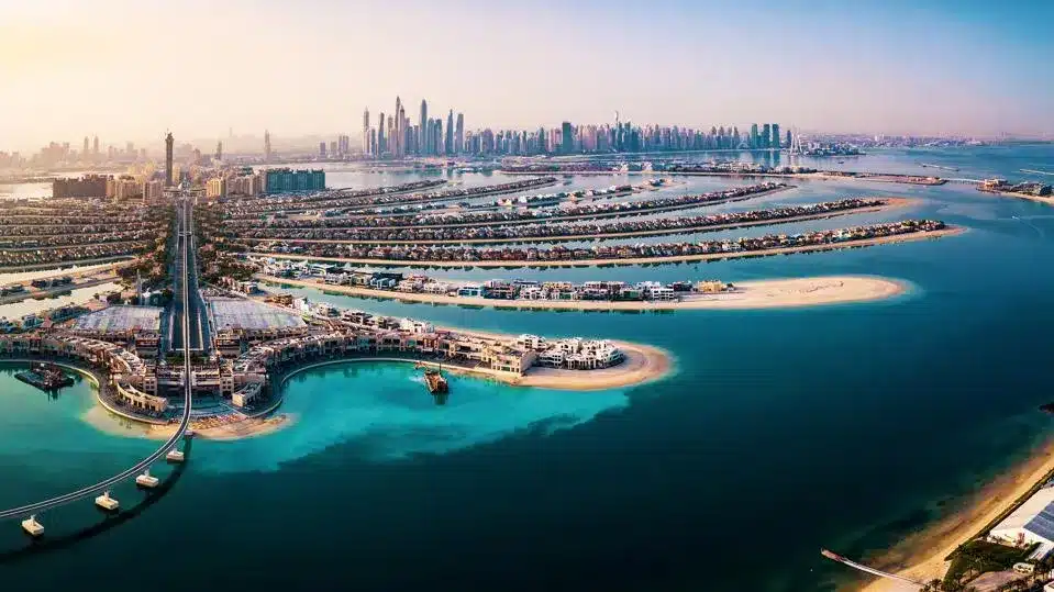 A breathtaking aerial view of Palm Jumeirah in Dubai, showcasing its unique palm-shaped islands, luxurious waterfront villas, and the city's iconic skyline in the background.







